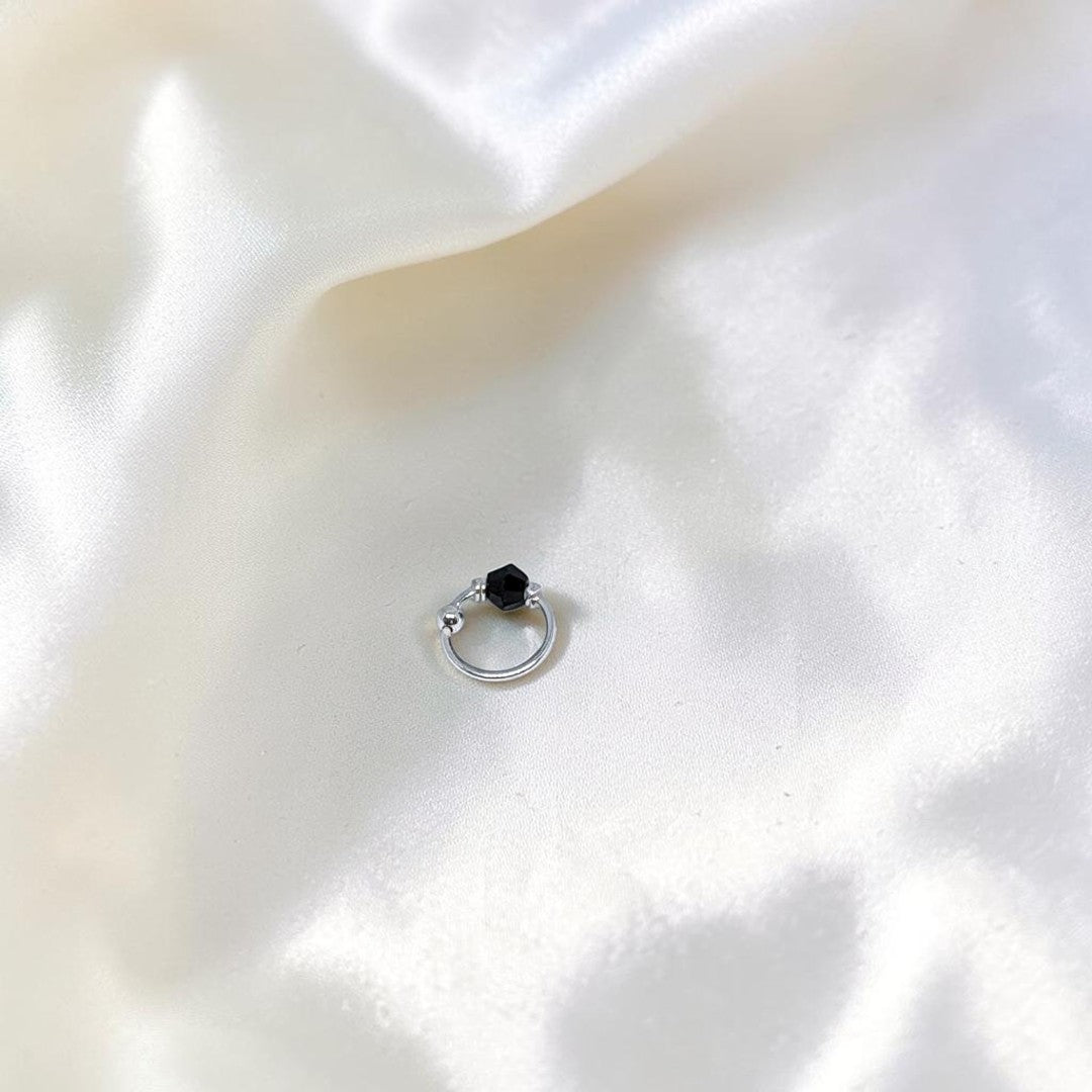 BlingbyAnvika 925 sterling silver nose ring featuring a small black bead on a white satin background