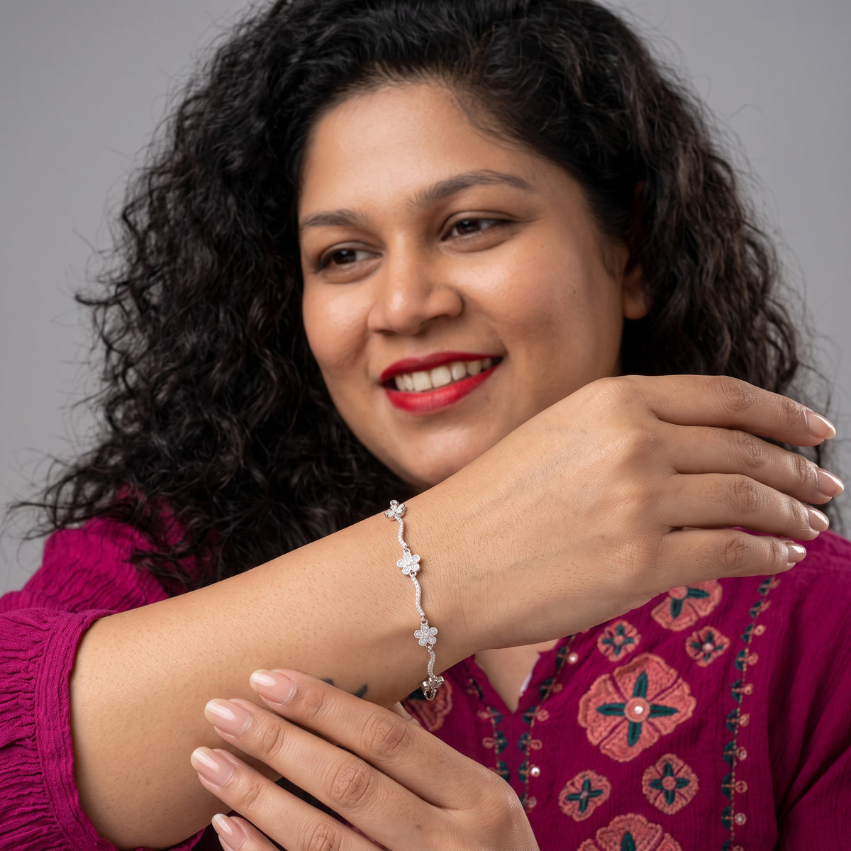 BlingbyAnvika 925 sterling silver flower bracelet with sparkling stones worn by a woman in a magenta top
