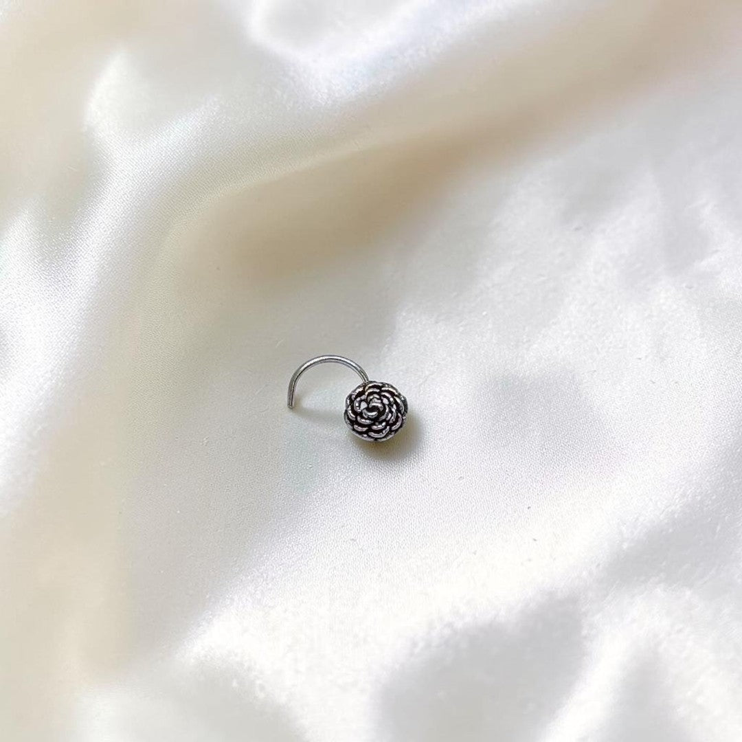 BlingbyAnvika 925 sterling silver nose pin featuring a delicate, detailed floral bloom design on white silk fabric.