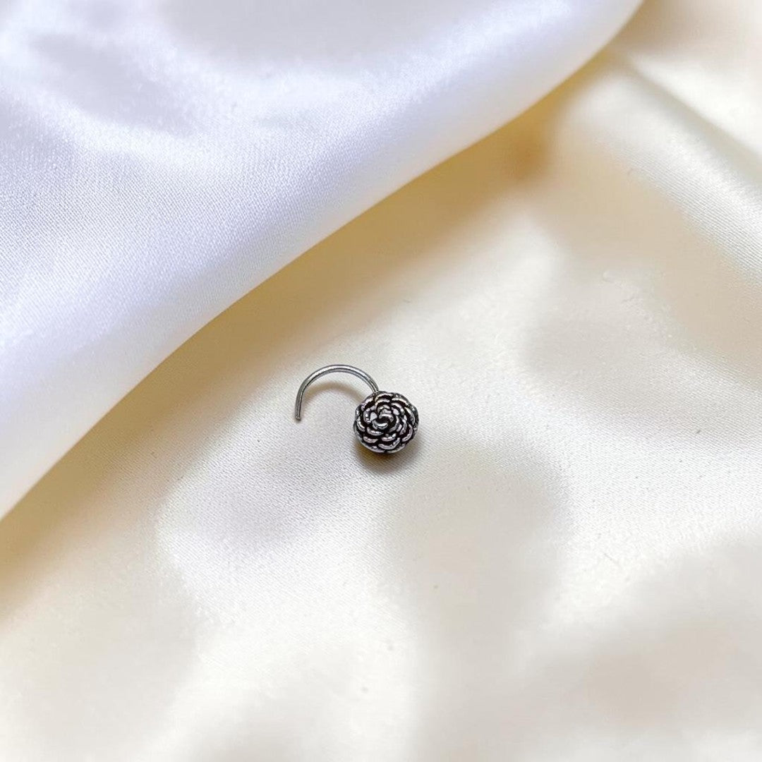 BlingbyAnvika 925 sterling silver nose pin featuring a delicate, detailed floral bloom design on white silk fabric.