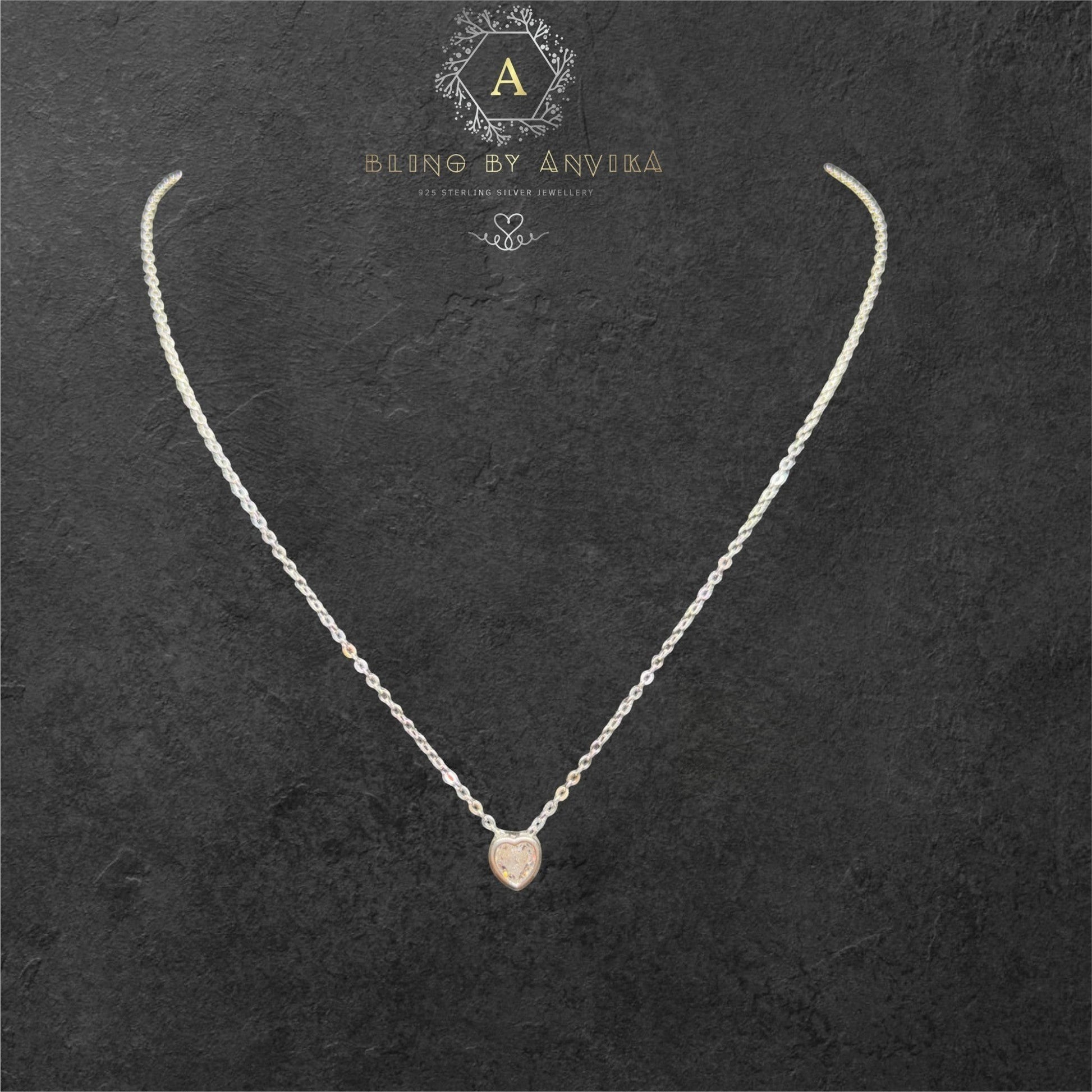 BlingbyAnvika 925 sterling silver heart pendant necklace on a delicate chain against a dark textured background