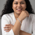 A woman wearing a BlingbyAnvika 925 sterling silver tennis bracelet with sparkling stones on her wrist