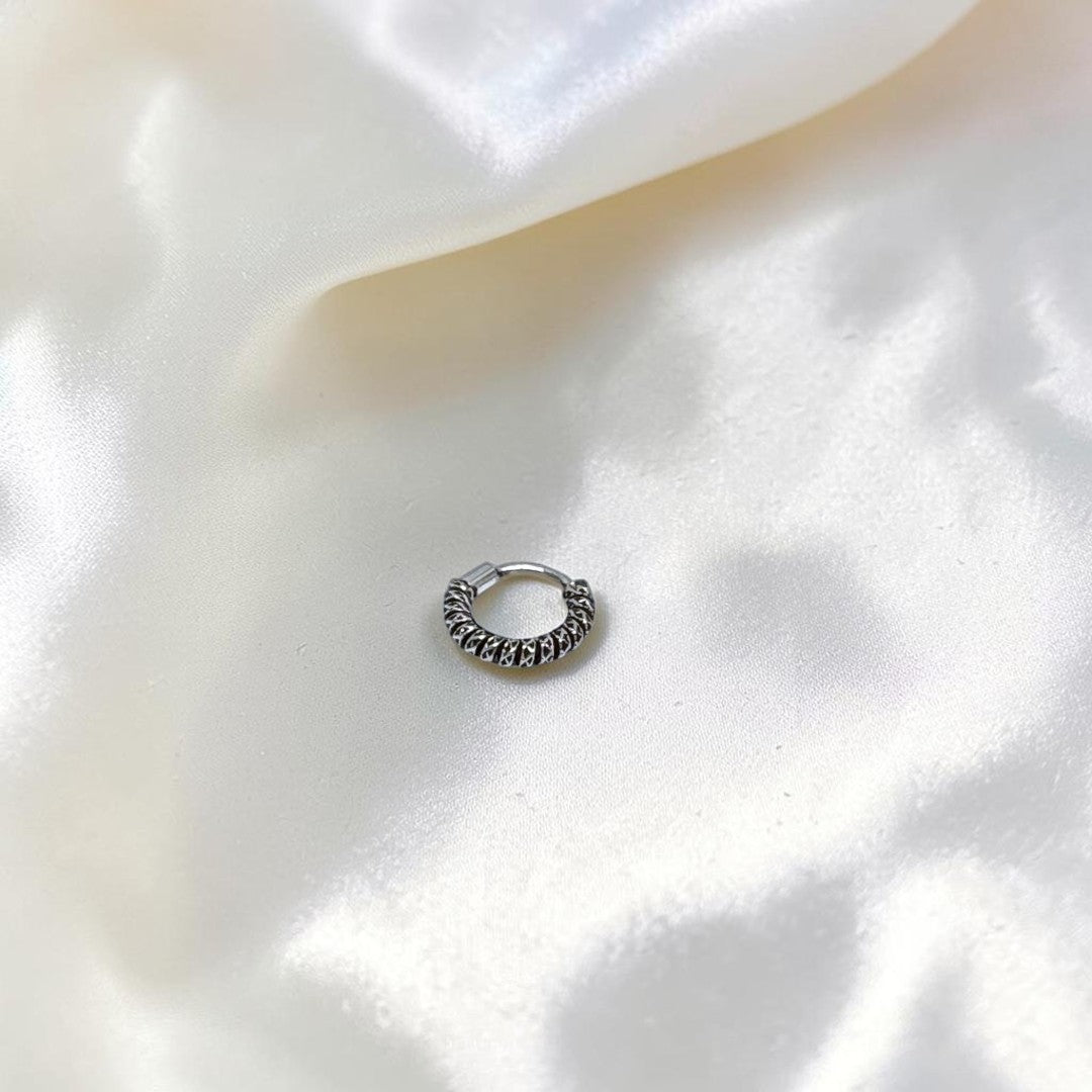 BlingbyAnvika 925 sterling silver nose ring with a twisted rope texture on a soft white satin background.
