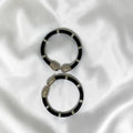 BlingbyAnvika pair of black cord bracelets with silver-tone lion head clasps and accents.