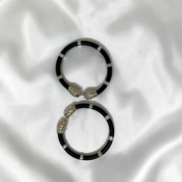 BlingbyAnvika pair of black cord bracelets with silver-tone lion head clasps and accents.