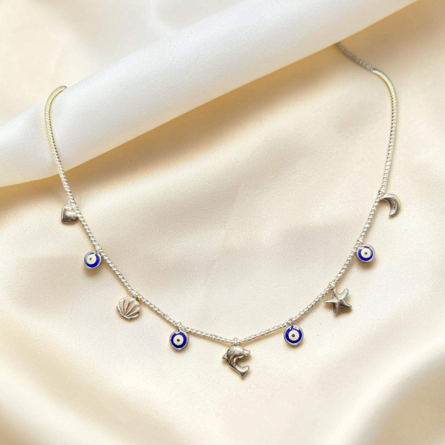BlingbyAnvika gold-tone short necklace with evil eye, heart, shell, dolphin, star, and moon charms.