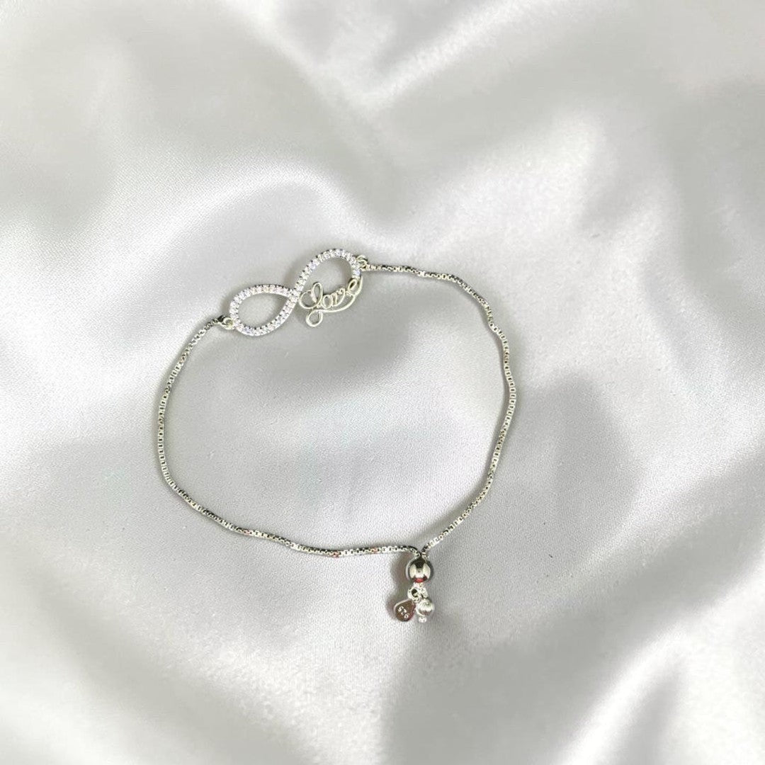 BlingbyAnvika sterling silver bracelet with infinity symbol, cubic zirconia, and 'love' charm. Features a dangling charm.