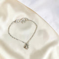 BlingbyAnvika sterling silver bracelet with infinity symbol, cubic zirconia, and 'love' charm. Features a dangling whimsical charm.