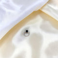 BlingbyAnvika 925 sterling silver nose ring featuring a small black bead on a smooth hoop against white silk fabric.