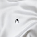 BlingbyAnvika 925 sterling silver nose ring featuring a small black bead on a white satin background.