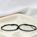 BlingbyAnvika 925 sterling silver and black thread Nazarband anklets on a soft white satin fabric background.