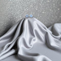 BlingbyAnvika 925 silver round blue gemstone stud earrings with polished bezel, displayed on grey satin.