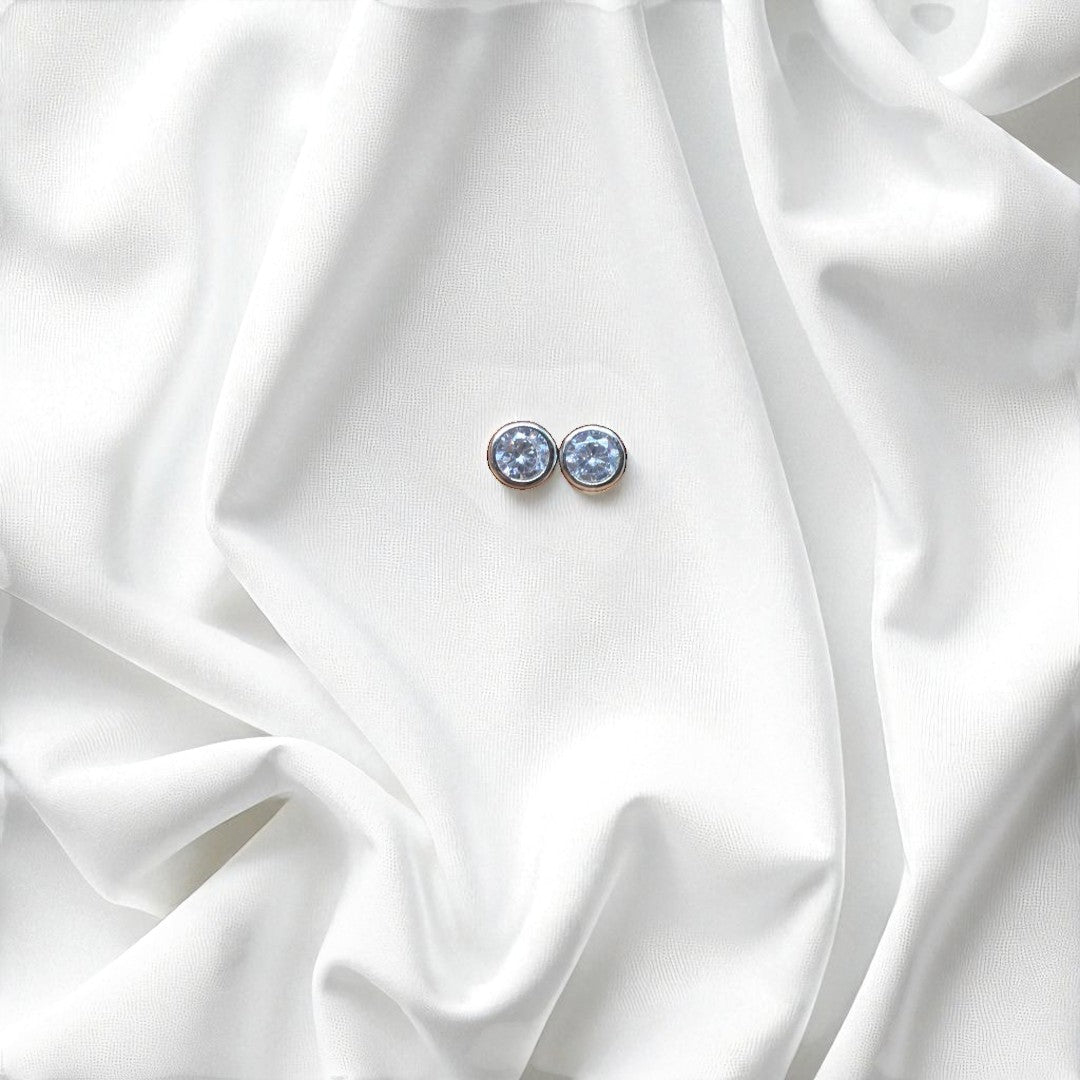 BlingbyAnvika 925 silver round blue gemstone stud earrings with polished bezel, set on white satin.