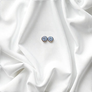BlingbyAnvika 925 silver round blue gemstone stud earrings with polished bezel, set on white satin.