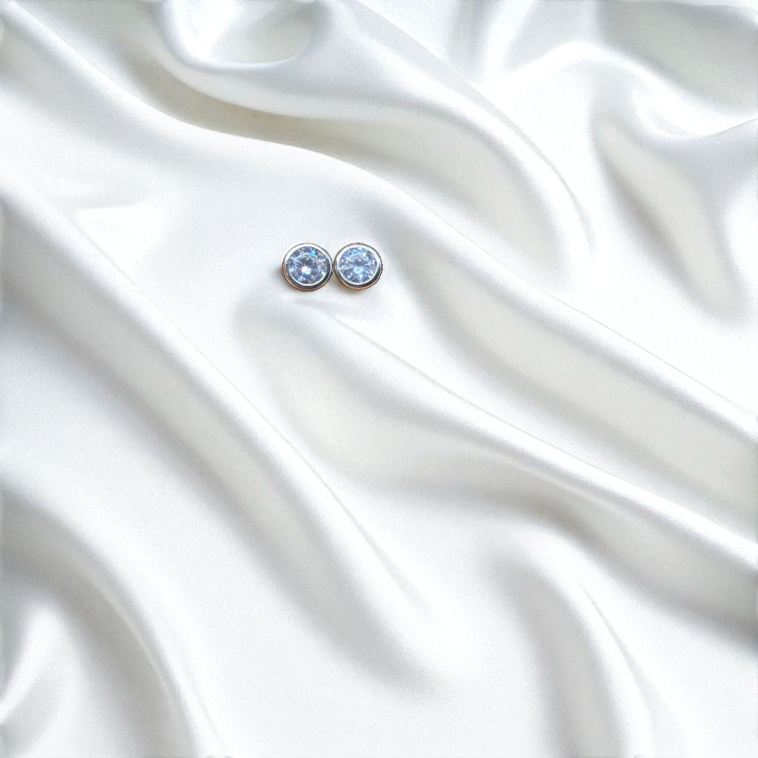 BlingbyAnvika 925 silver round blue gemstone stud earrings with polished bezel, set on white satin.