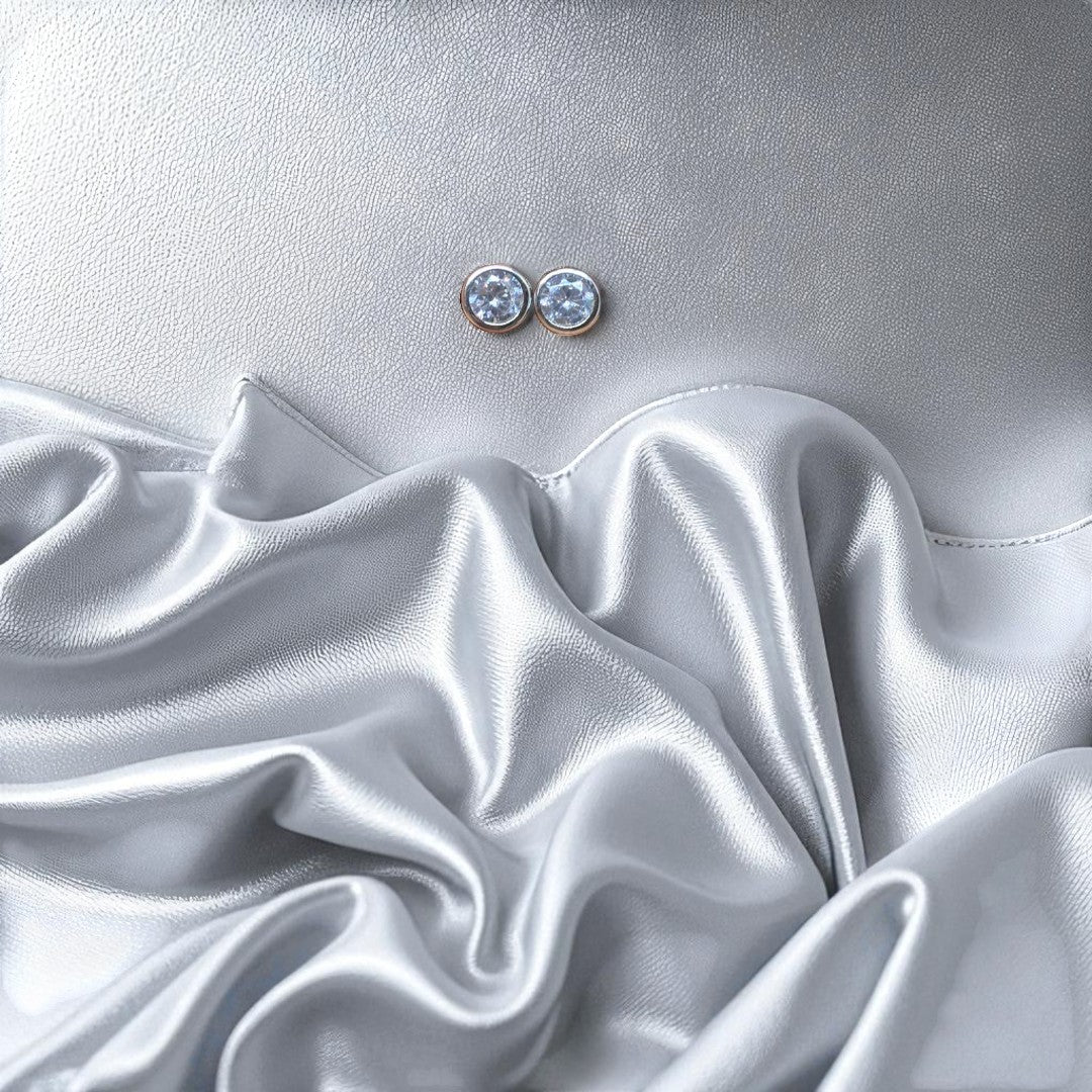 BlingbyAnvika 925 silver round blue gemstone stud earrings with polished bezel, set against a silver satin background.