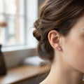 BlingbyAnvika sterling silver stud earrings with a brilliant-cut white cubic zirconia stone worn on an earlobe.