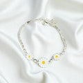 BlingbyAnvika 925 silver bracelet featuring white daisy charms with yellow centers and clear stone accents on a chain.