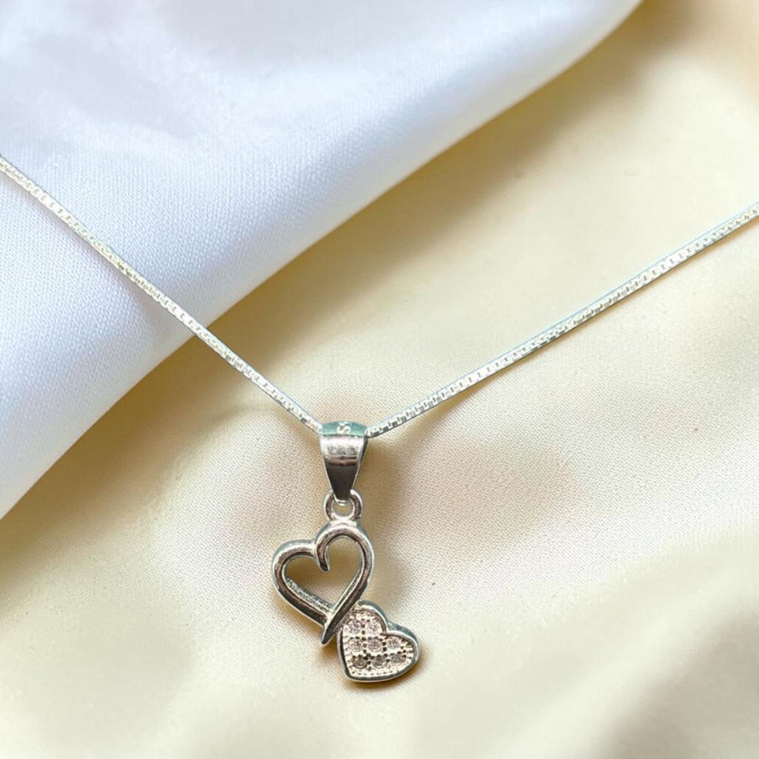 BlingbyAnvika sterling silver pendant with two interlocking hearts, one adorned with small stones.