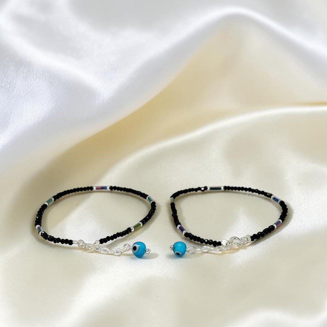 BlingbyAnvika 925 sterling silver and black thread anklets featuring blue evil eye Nazarband charms on satin fabric.