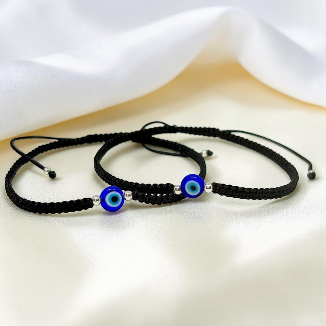 BlingbyAnvika black thread anklets featuring blue evil eye charms and 925 sterling silver beads on white fabric.