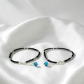BlingbyAnvika 925 sterling silver evil eye anklets with black beaded thread on a white satin background.