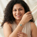 BlingbyAnvika 925 silver floral bracelet with a central green stone and white crystal petals worn by a smiling woman