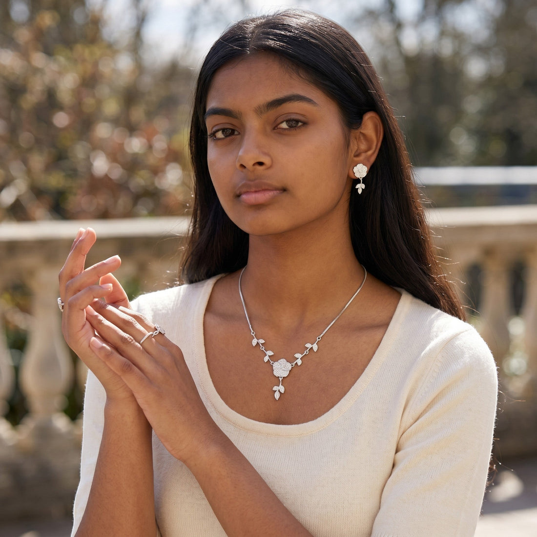 BlingbyAnvika 925 sterling silver floral necklace and matching stud earrings set on a white satin background.