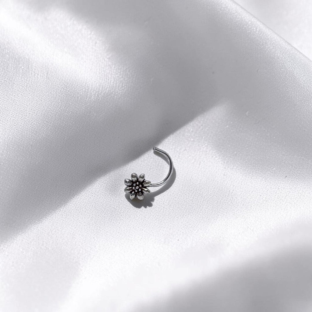 BlingbyAnvika 925 sterling silver nose pin featuring a delicate floral design on a soft white satin background.