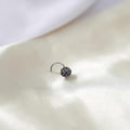 BlingbyAnvika 925 sterling silver nose pin featuring a detailed floral design on a soft white satin background.