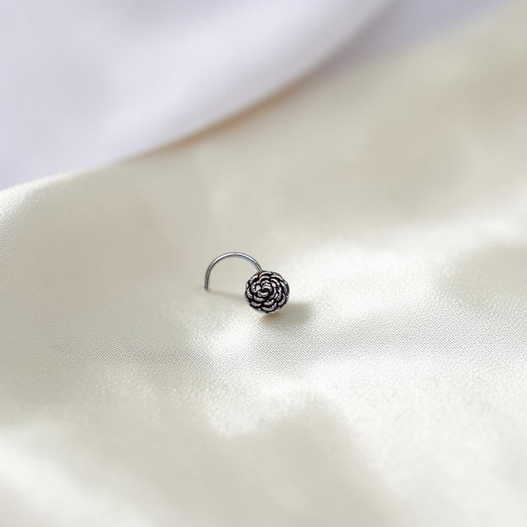 BlingbyAnvika 925 sterling silver nose pin featuring a detailed floral design on a soft white satin background.