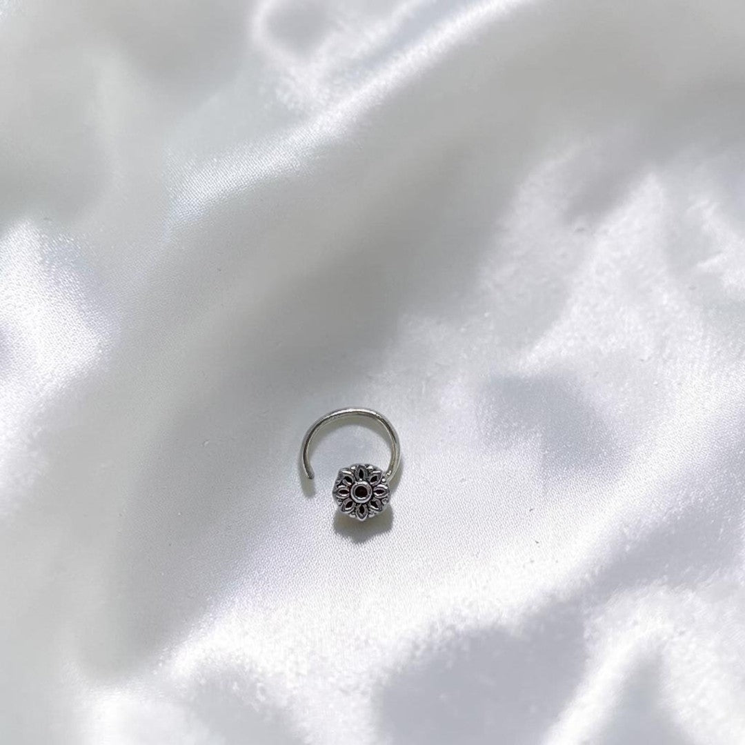BlingbyAnvika 925 sterling silver nose pin featuring a delicate floral design on a textured grey surface