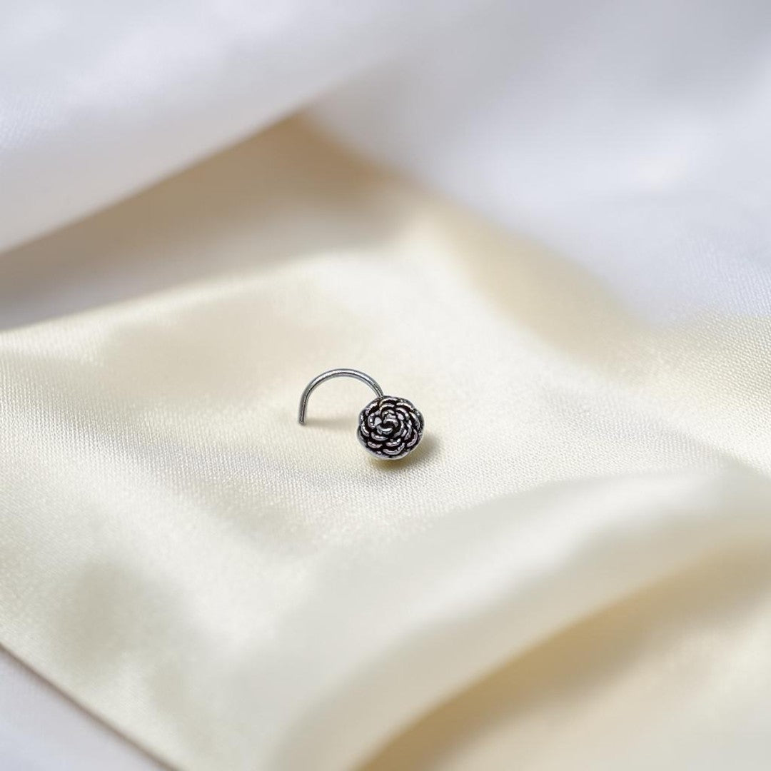 BlingbyAnvika 925 sterling silver nose pin featuring a delicate floral bloom design on a white satin background.