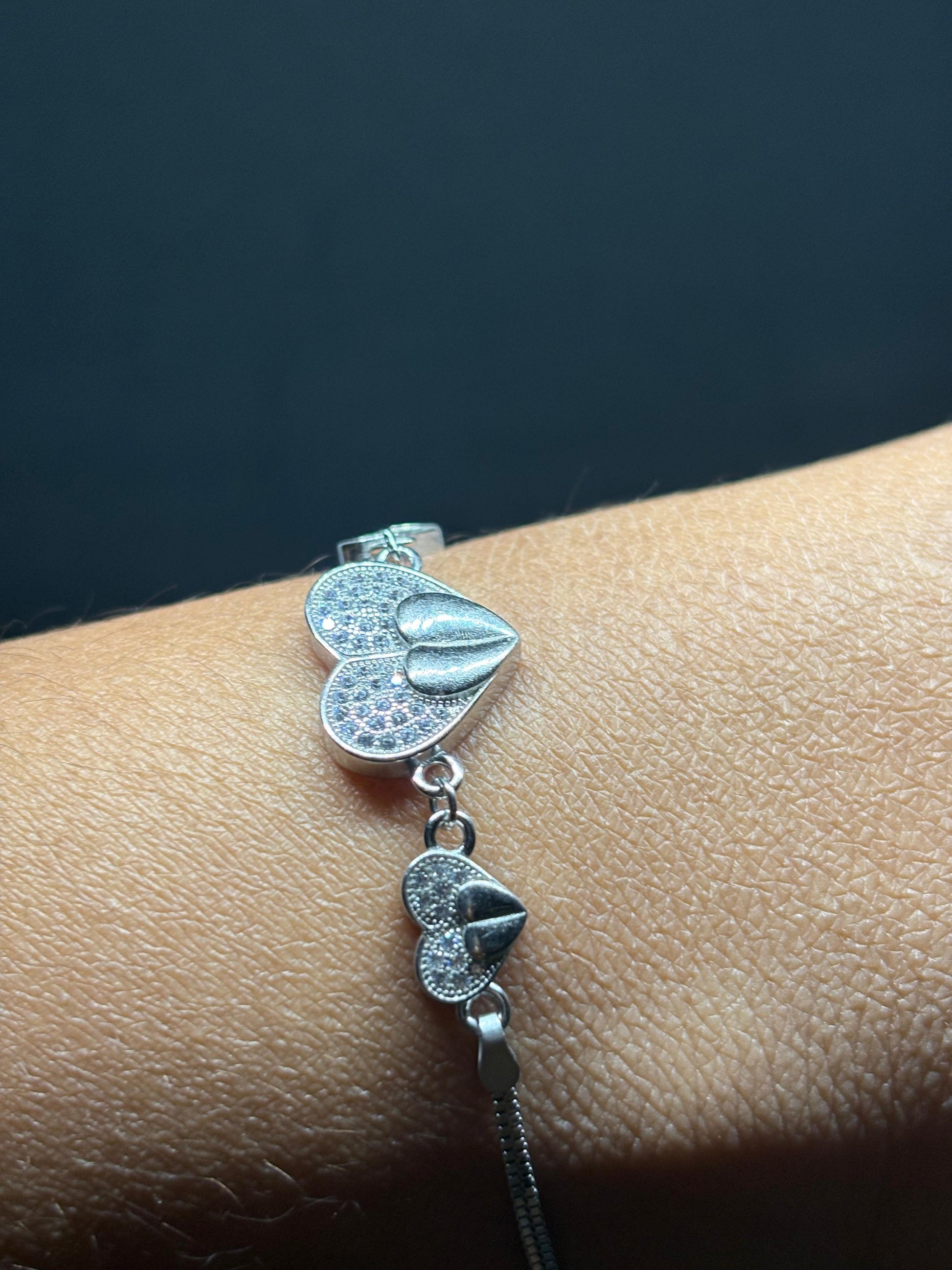 BlingbyAnvika 925 sterling silver bracelet with multiple heart charms, some encrusted with small clear stones.
