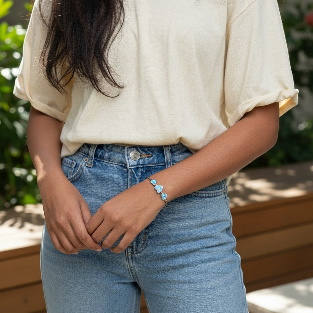 BlingbyAnvika 925 sterling silver bracelet with light blue enamel heart charms on a woman's wrist.