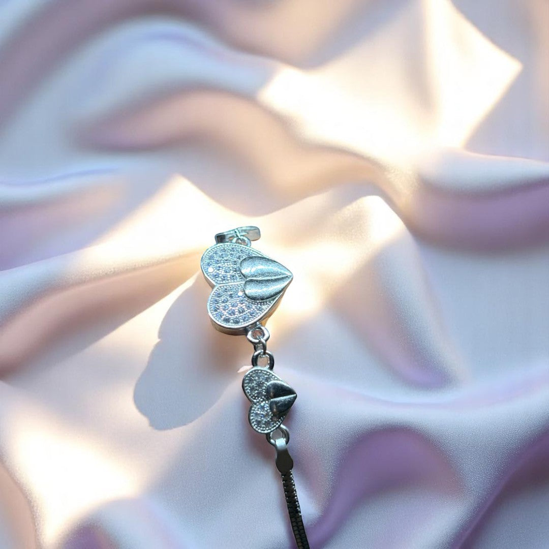 BlingbyAnvika 925 sterling silver bracelet with two heart charms, one large and one small, adorned with cubic zirconia. Delicate chain and secure clasp.