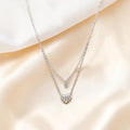 BlingbyAnvika sterling silver double-strand necklace with a small gold heart and a larger crystal-embellished silver heart pendant.
