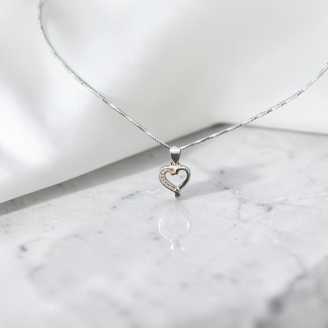 BlingbyAnvika 925 sterling silver heart pendant necklace with delicate chain on white satin fabric