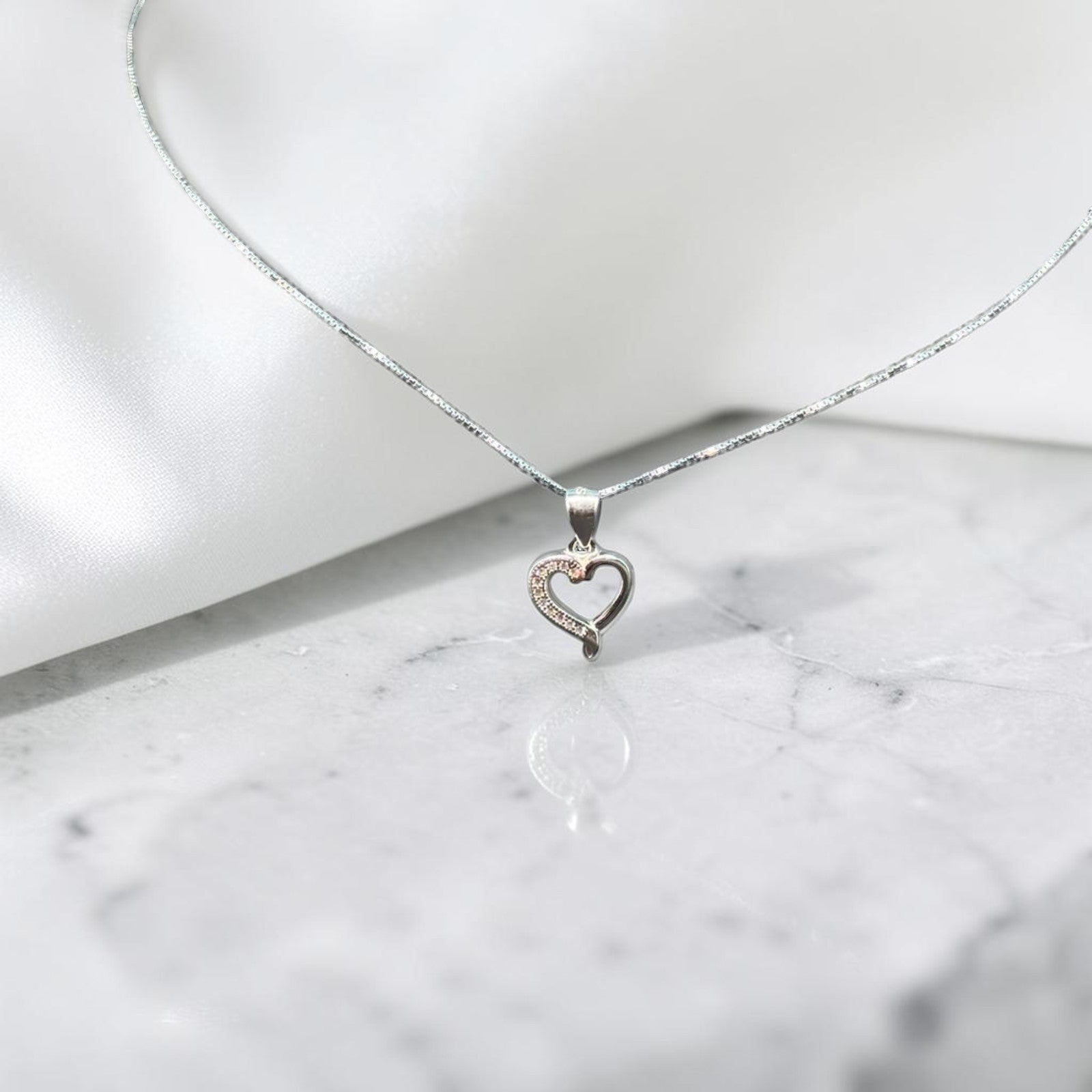 BlingbyAnvika 925 sterling silver heart pendant necklace with delicate chain on a white satin background