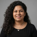 Woman wearing a BlingbyAnvika layered sterling silver heart pendant necklace against a grey background
