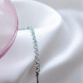 BlingbyAnvika 925 sterling silver bracelet with a row of small, sparkling heart-shaped stones on a white satin background.