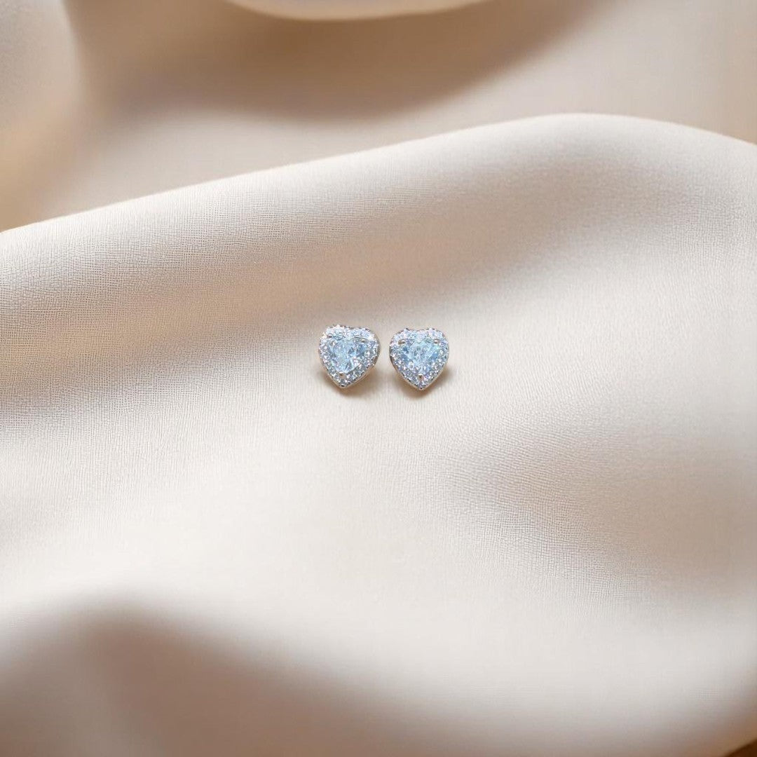 BlingbyAnvika heart-shaped stud earrings in 925 sterling silver with sparkling AAA-grade zircon stones on silk fabric.