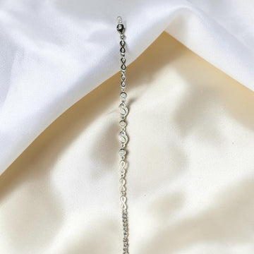 BlingbyAnvika 925 silver infinity link chain bracelet with sparkling accents on a soft white satin background