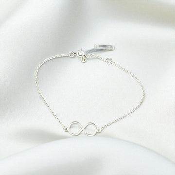 BlingbyAnvika 925 sterling silver infinity symbol bracelet with a delicate chain on a white satin background