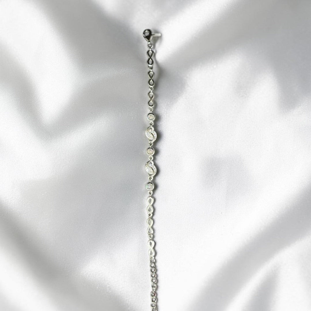 BlingbyAnvika 925 silver infinity link chain bracelet with sparkling accents on a white satin background