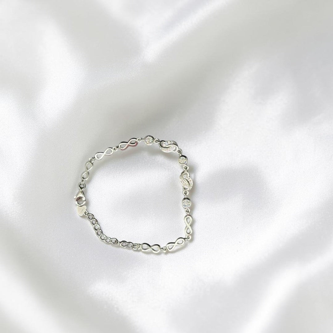 BlingbyAnvika 925 silver infinity link chain bracelet with sparkling accents on a white satin background