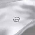 BlingbyAnvika 925 sterling silver nose ring featuring a delicate hanging leaf charm on a white satin background.