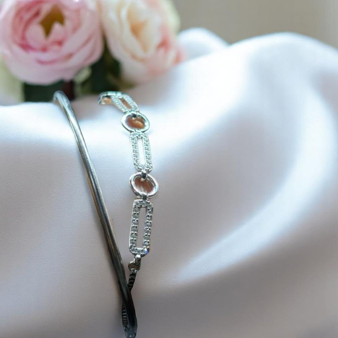 BlingbyAnvika 925 silver linked chain bracelet with pavé accents and a sleek kada bangle on white satin fabric.