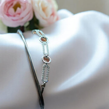 BlingbyAnvika 925 silver linked chain bracelet with pavé accents and a sleek kada bangle on white satin fabric.