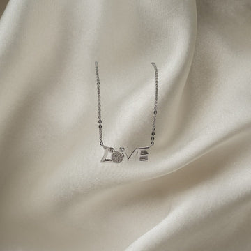 BlingbyAnvika 925 sterling silver necklace with the word LOVE in script, featuring a circular charm with small stones on the letter O.